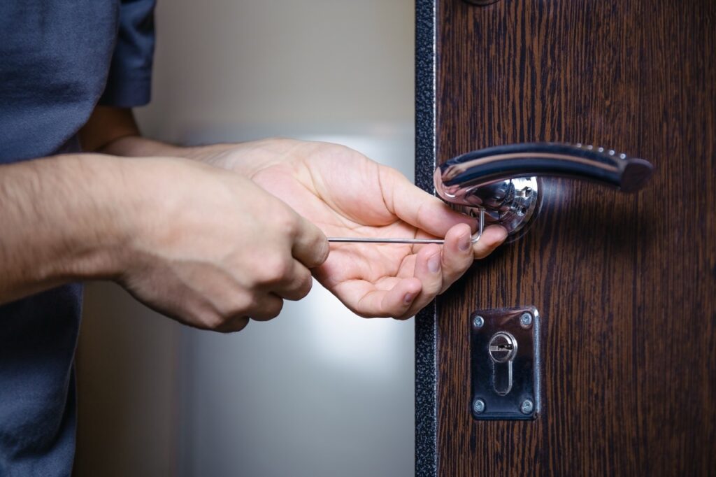 Close-up of male hands repair or installing a metal door lock with a screwdriver. Improved robbery protection.