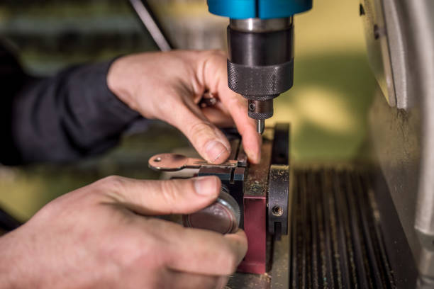 Close-up of a locksmith's hands carefully operating a key duplicating machine, creating a precise copy of a metal key, showcasing the precision and skill involved in the key cutting process